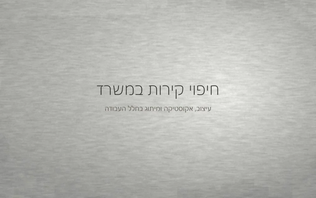 קיר במרקם מינרלי עדין בגוון אפור בהיר, מואר באור צד רך של חלל עבודה