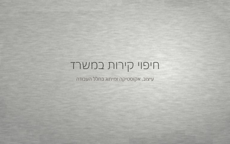 קיר במרקם מינרלי עדין בגוון אפור בהיר, מואר באור צד רך של חלל עבודה
