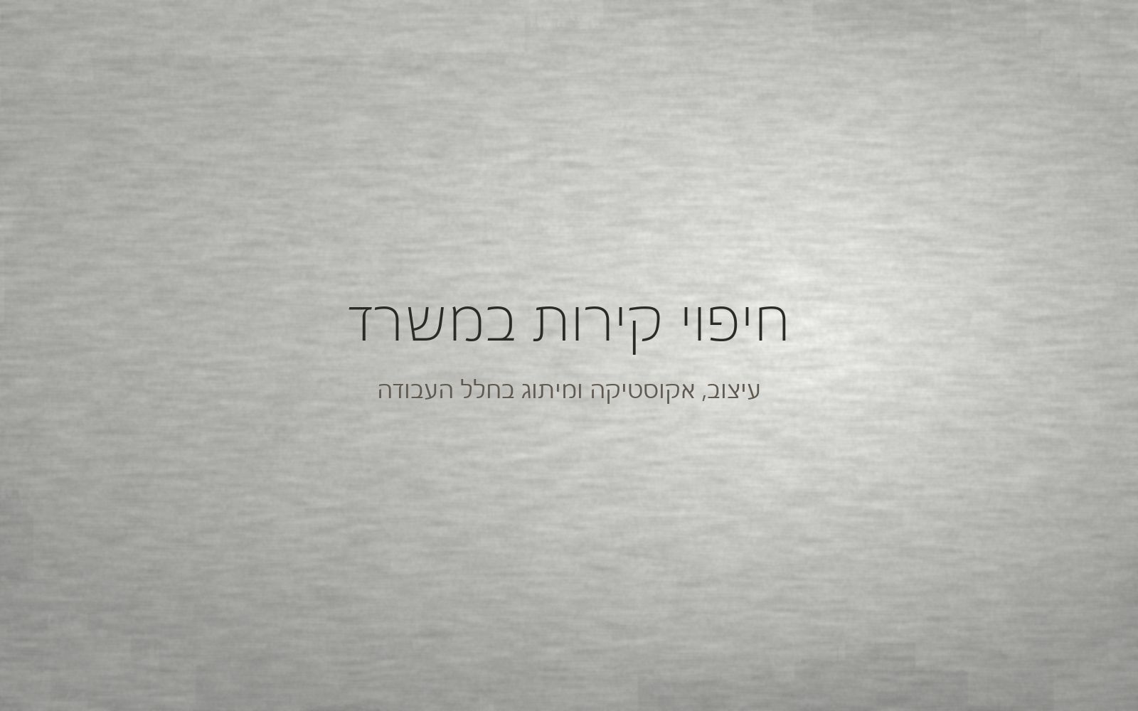 קיר במרקם מינרלי עדין בגוון אפור בהיר, מואר באור צד רך של חלל עבודה